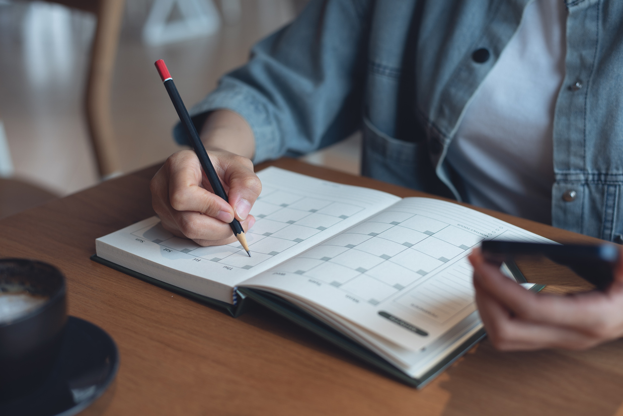 View of a person making notes in a planner booklet.